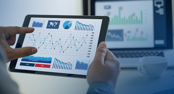 Ihmisen käsissä on tabletti, jossa näkyy kaavioita